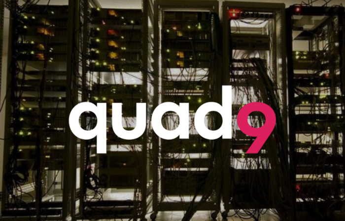 dark room with light coming through the other side of a row of tangled computer servers q9 logo up front