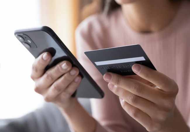 Woman holding phone and card in living room