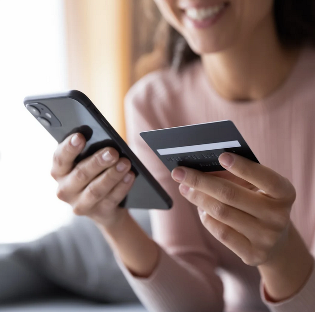 Woman holding phone and card in living room