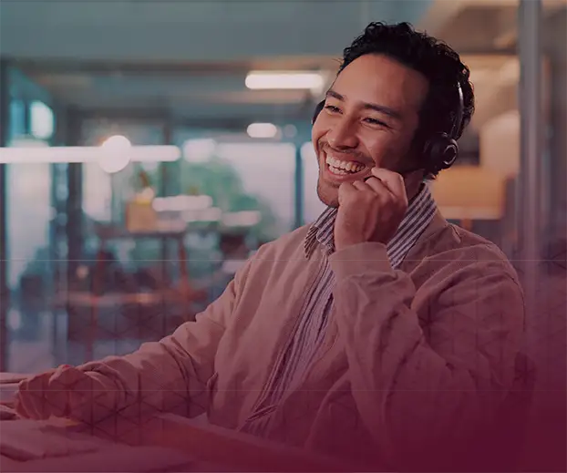 A man wearing a headset smiling as he talks into the microphone.