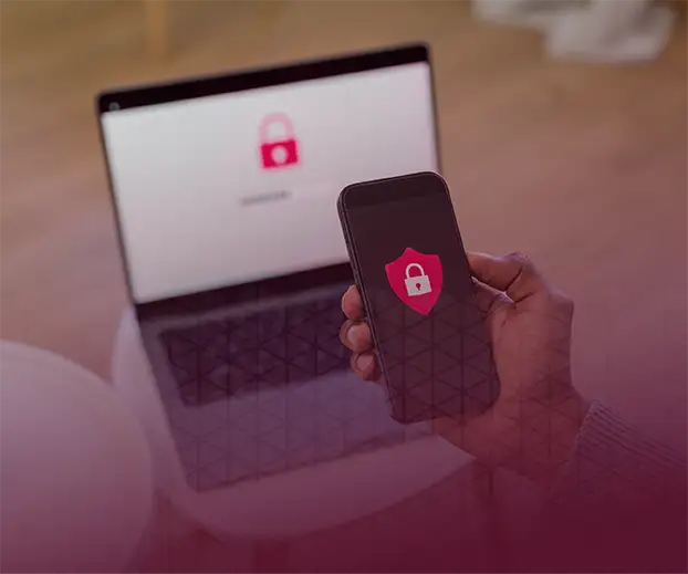 Image of a computer and a person holding a mobile phone with a red security icon.