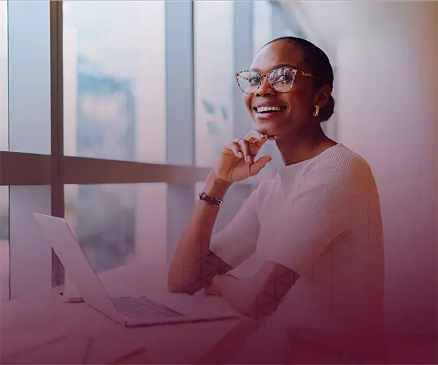 Image of a black woman smiling in front of a computer.